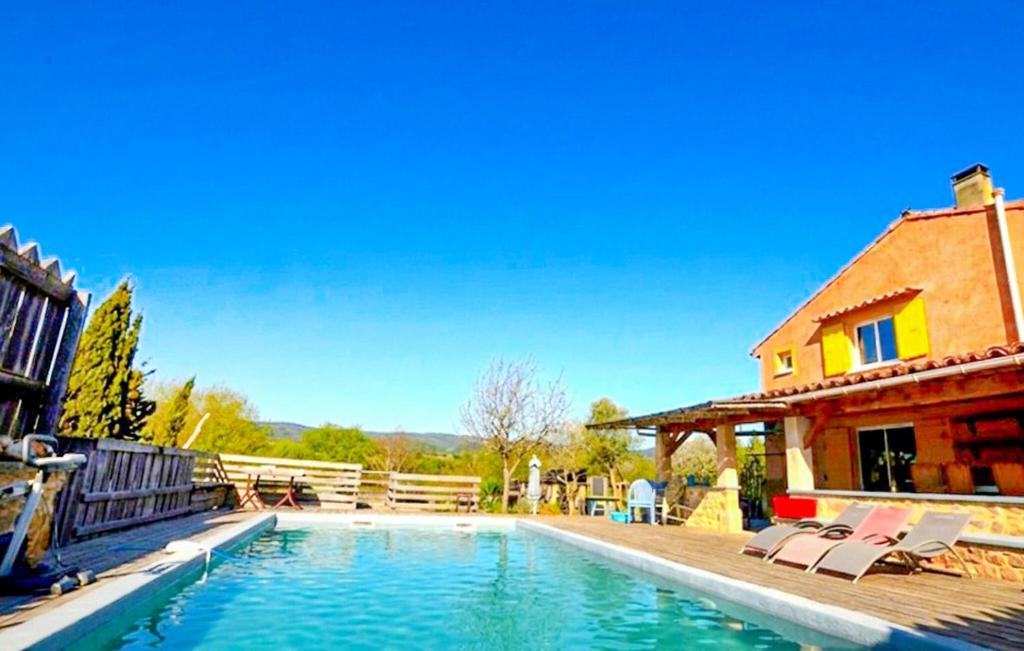 a swimming pool with chairs and a house at Authentique Maison Piscine in La Cassaigne