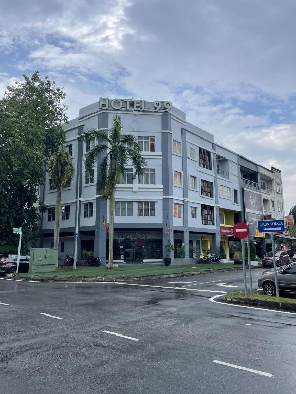 a hotel building with a palm tree in front of a street at Hotel 99 Kota Kemuning in Shah Alam