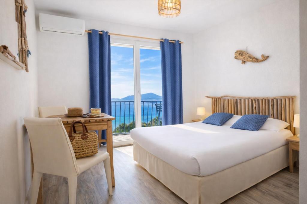a bedroom with a bed and a table and a window at Hôtel Almanarre Plage - Hôtel Eco-Responsable face à la mer in Hyères