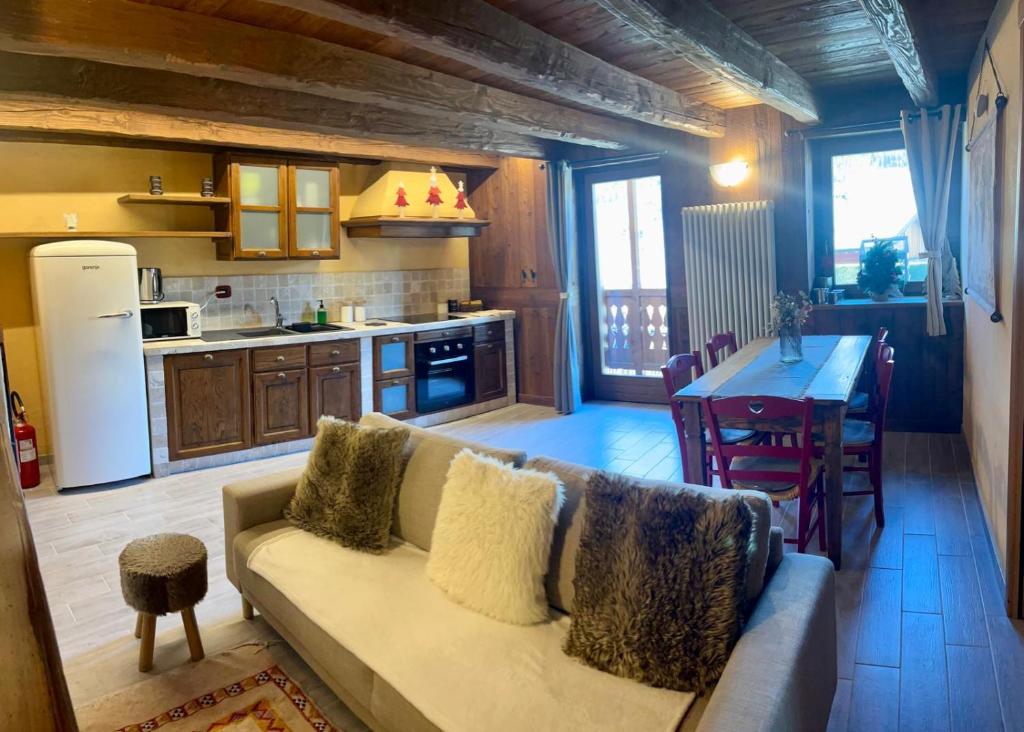 ein Wohnzimmer mit Sofa und eine Küche mit Tisch in der Unterkunft Tsi nos La Salle appartamento con giardino e balcone in La Salle
