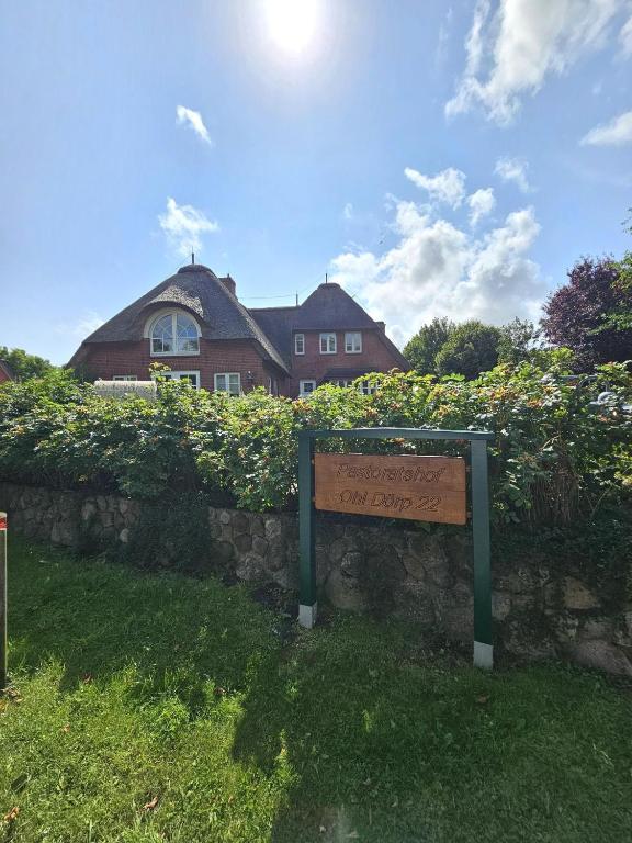 a sign in front of a stone wall with a house at Pastoratshof - Haus 6 in Wrixum