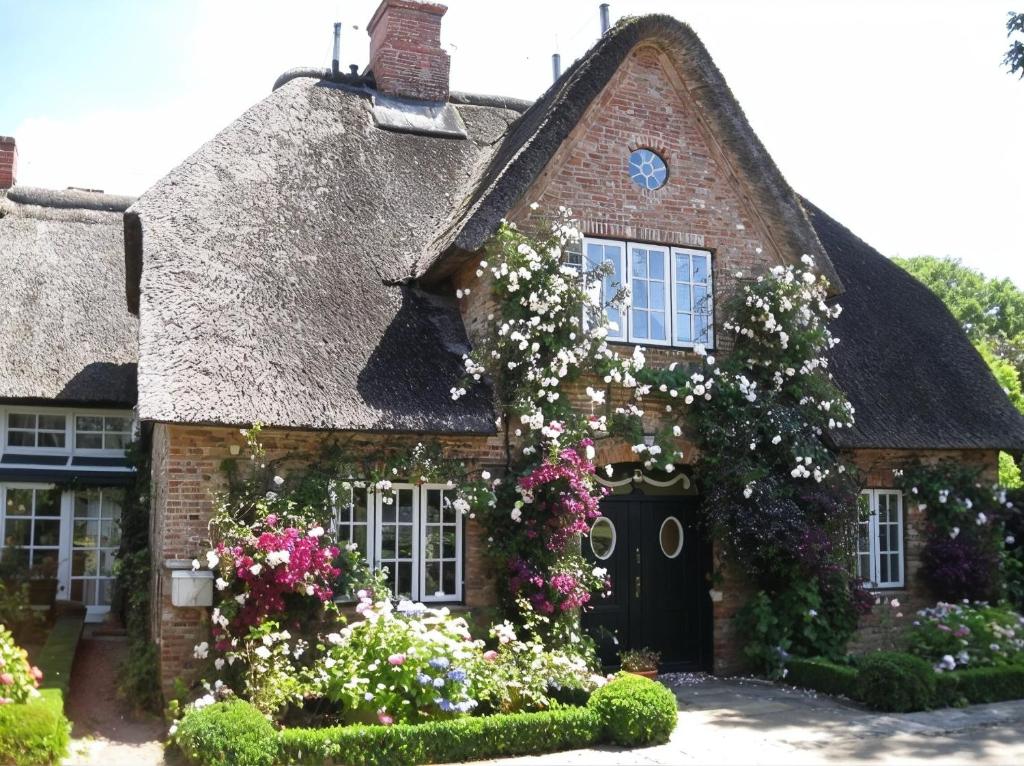 an old house with flowers in front of it at Reethus Haupthaus im EG OG in Borgsum