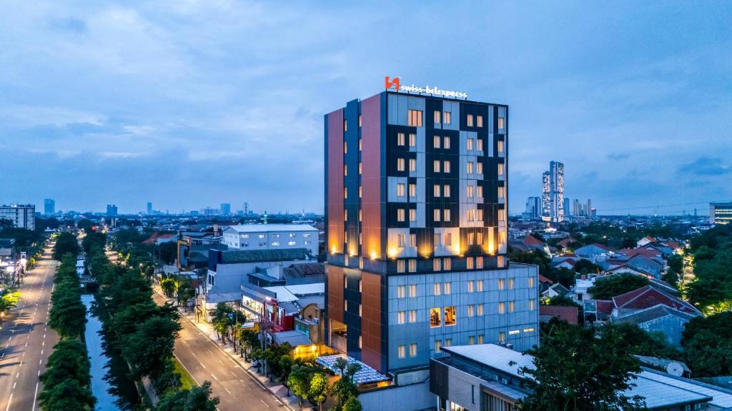 a tall building with a sign on top of it at Swiss-Belexpress Jemursari in Surabaya