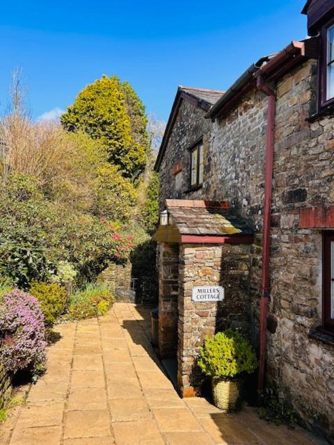 an old stone building with a sign on it at Miller's Cottage in Woolfardisworthy