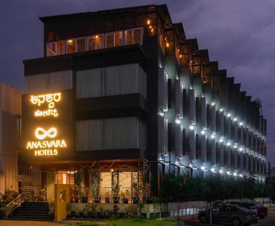 a building with a sign in front of it at night at Anasvara Hotels in Mysore