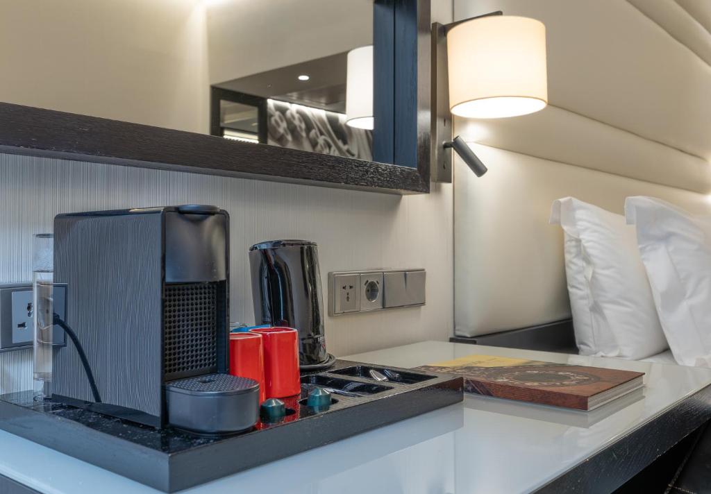 A bedside beverage station with a coffee machine, kettle, and cups.