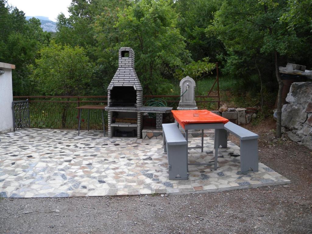 a picnic table and bench on a stone patio at Apartment Jablanac 1 in Jablanac