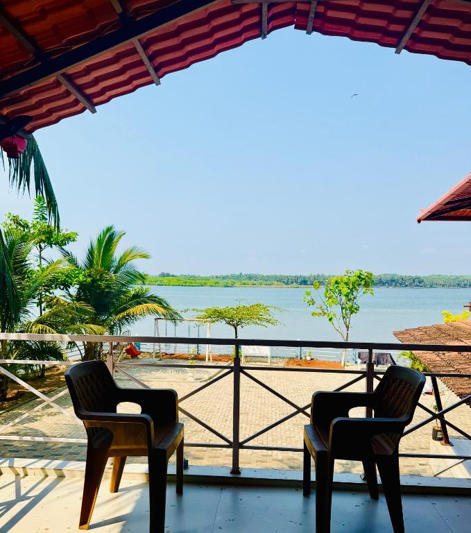 two chairs on a porch with a view of the water at Stay by the Backwater in Kalyānpur