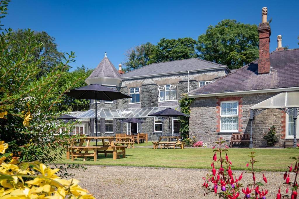 a house with tables and umbrellas in front of it at Broadway Country House in Laugharne