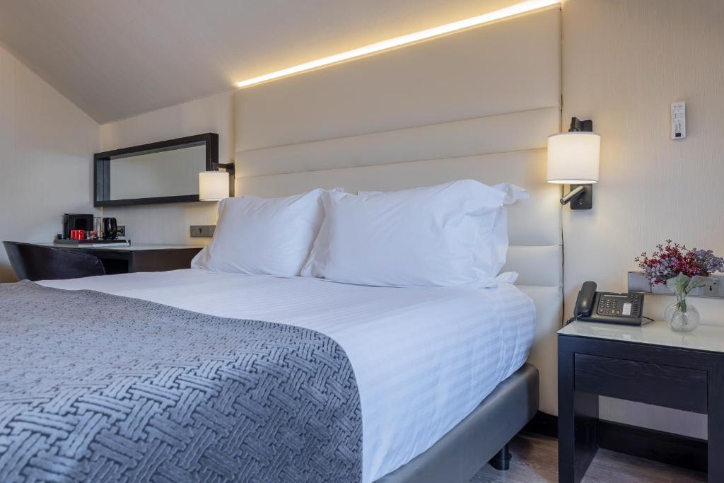 A bright bedroom centred on a large bed with a padded headboard.