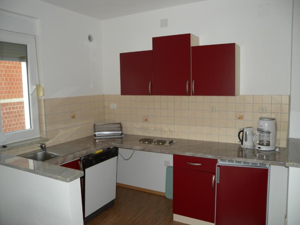 a kitchen with red and white cabinets and a sink at Apartment Liznjan 2 in Ližnjan