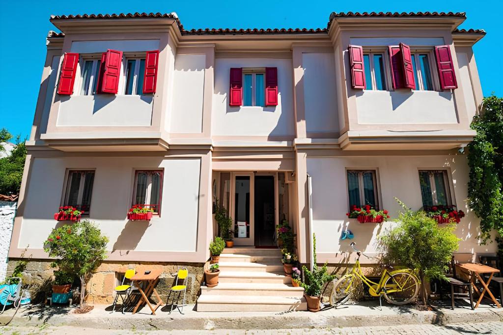 a house with red and blue shutters at Bozcaada Biz Otel in Bozcaada