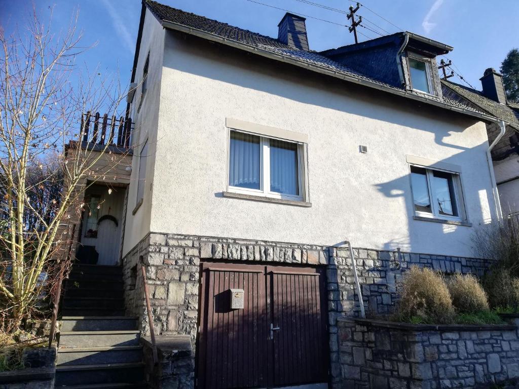 a white house with a gate and a stone wall at Ferienhaus Soonwald in Schwarzerden