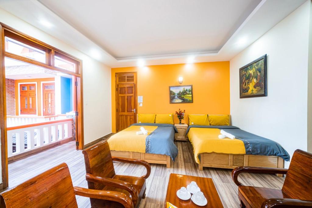 two beds in a room with yellow walls at Anh Trang Homestay in Da Lat