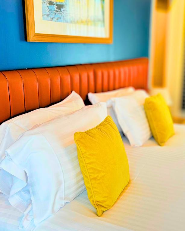 a bed with white and yellow pillows on it at Haslar Rooms in Gosport