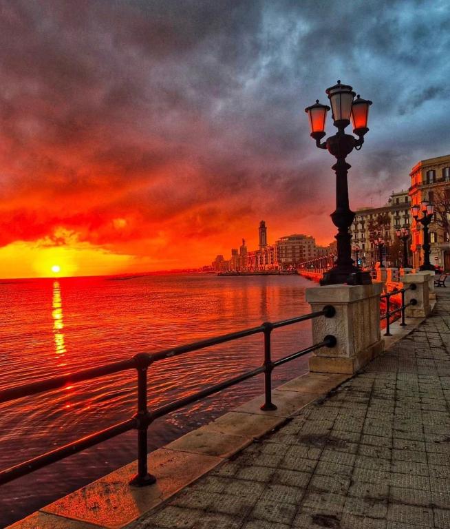 a street light next to the water with a sunset at Heart Of Bari in Bari