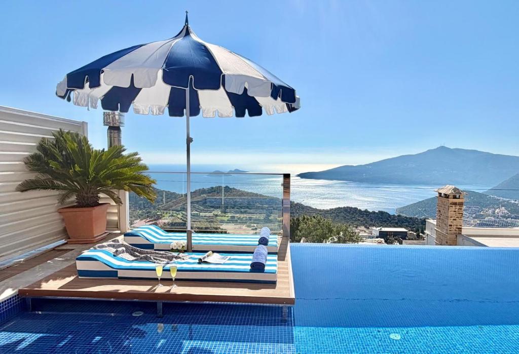 a pool with an umbrella and a bed and a swimming pool at Villa La Mer in Kalkan