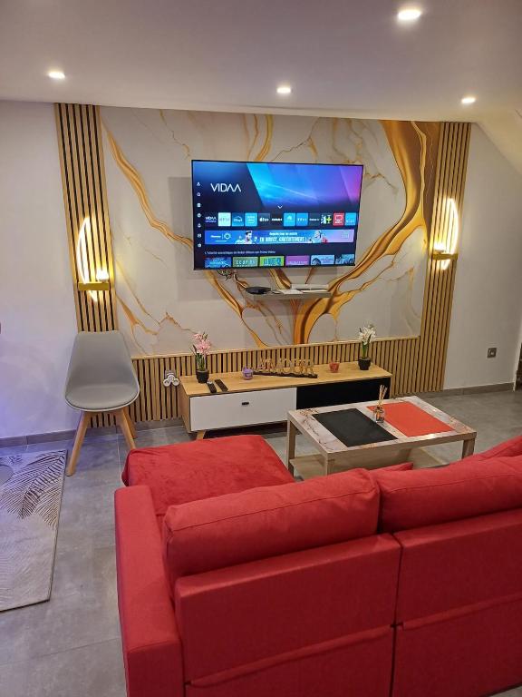 a living room with a red couch and a large tv at glamour chic maison de 70 m2 in Montluçon