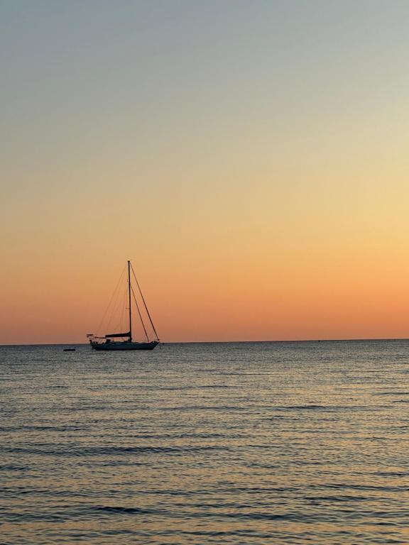 a boat in the ocean at sunset at Fenareti Apartments in Skala Eresou