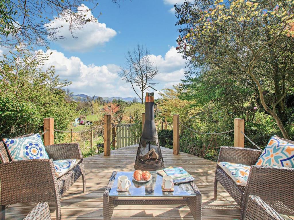 a patio with chairs and a fireplace on a wooden deck at 1 Bed in Denbigh oc-91890 in Llanrhaiadr