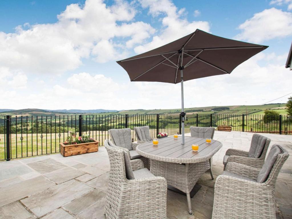 a patio with a table and chairs and an umbrella at 4 Bed in Denbigh oc-62368 in Denbigh