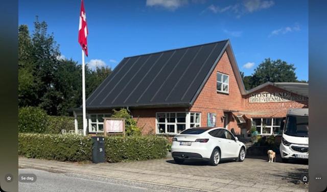 a white car parked in front of a house with a flag at Bøllingsø Bed and Breakfast in Engesvang