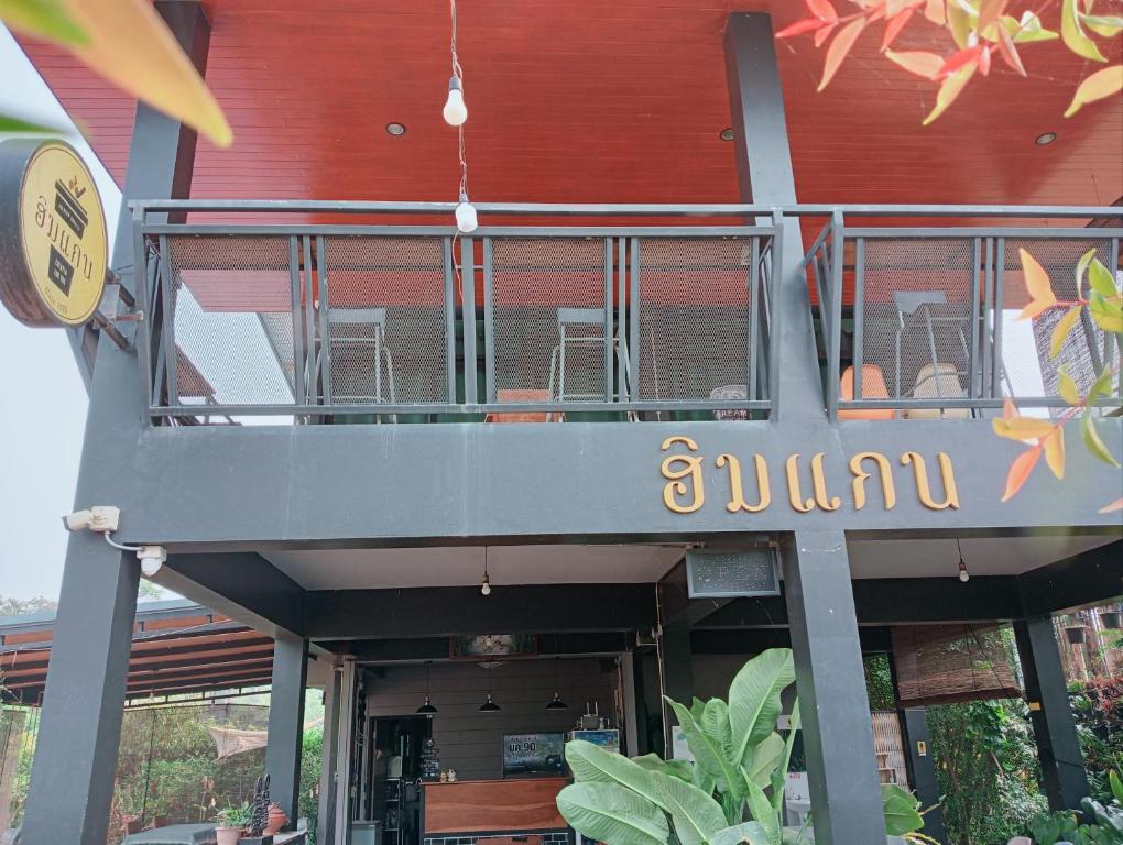 a building with a balcony with tables and chairs at ฮิมแกนแฟมิลี่เฮ้าส์ in Ban Pong (2)