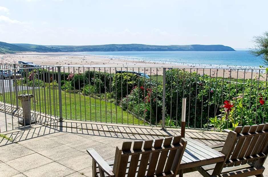 two benches sitting on a patio looking at the beach at Cliffside Garden Flat in Woolacombe