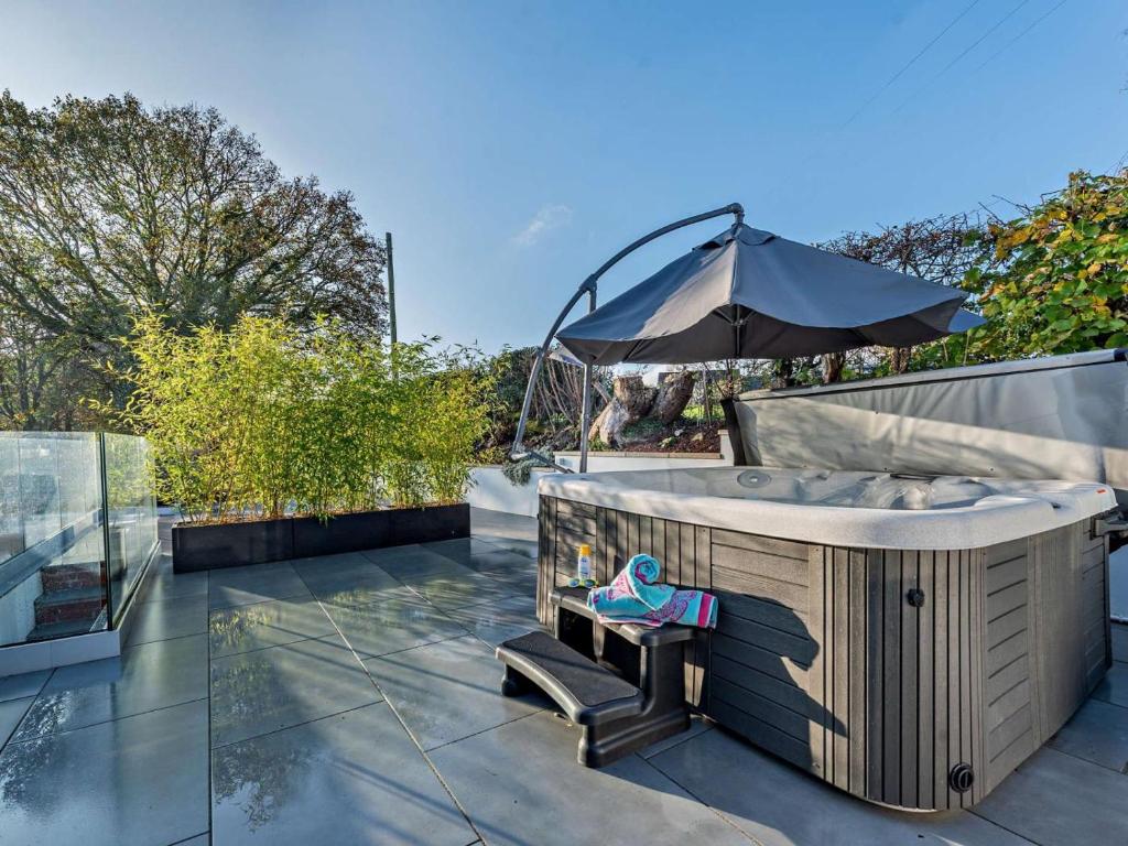 a hot tub on a patio with an umbrella at 4 Bed in Llandovery oc-90307 in Myddfai
