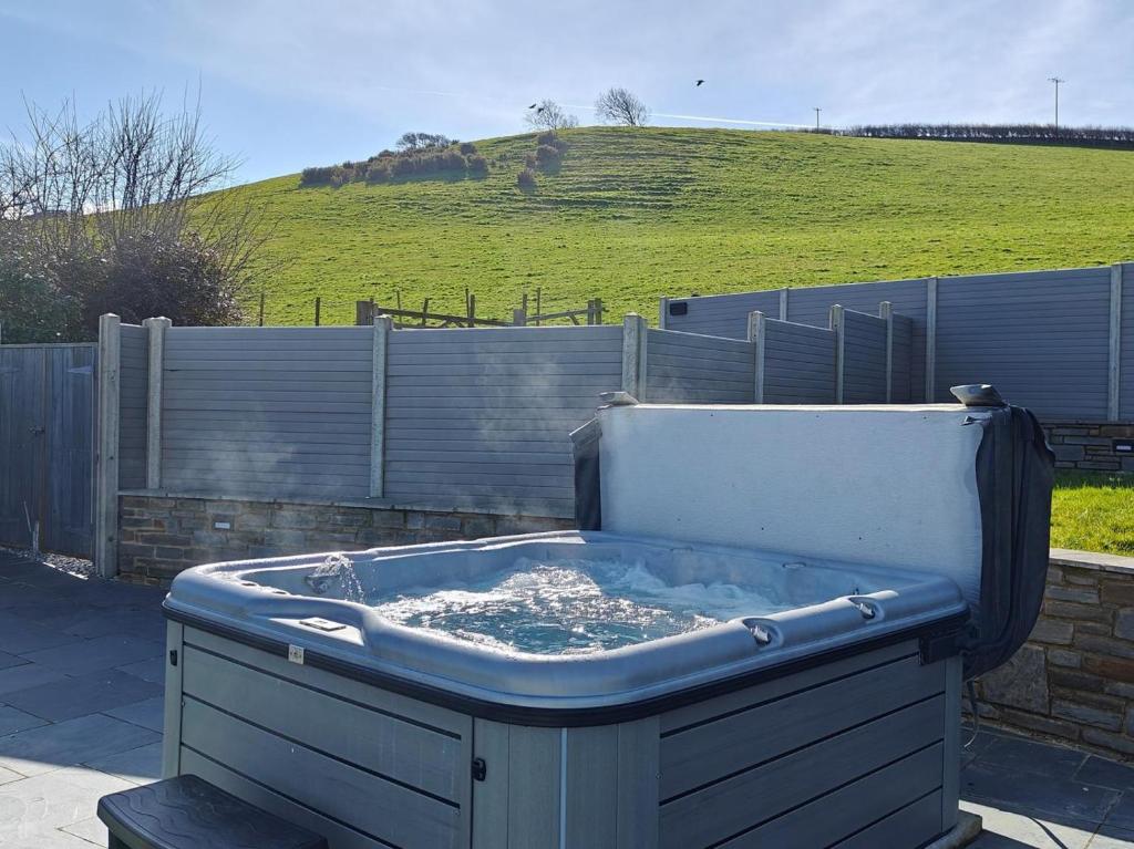 a hot tub sitting in a yard with a hill at 3 Bed in Aberaeron oc-95971 in Aberaeron