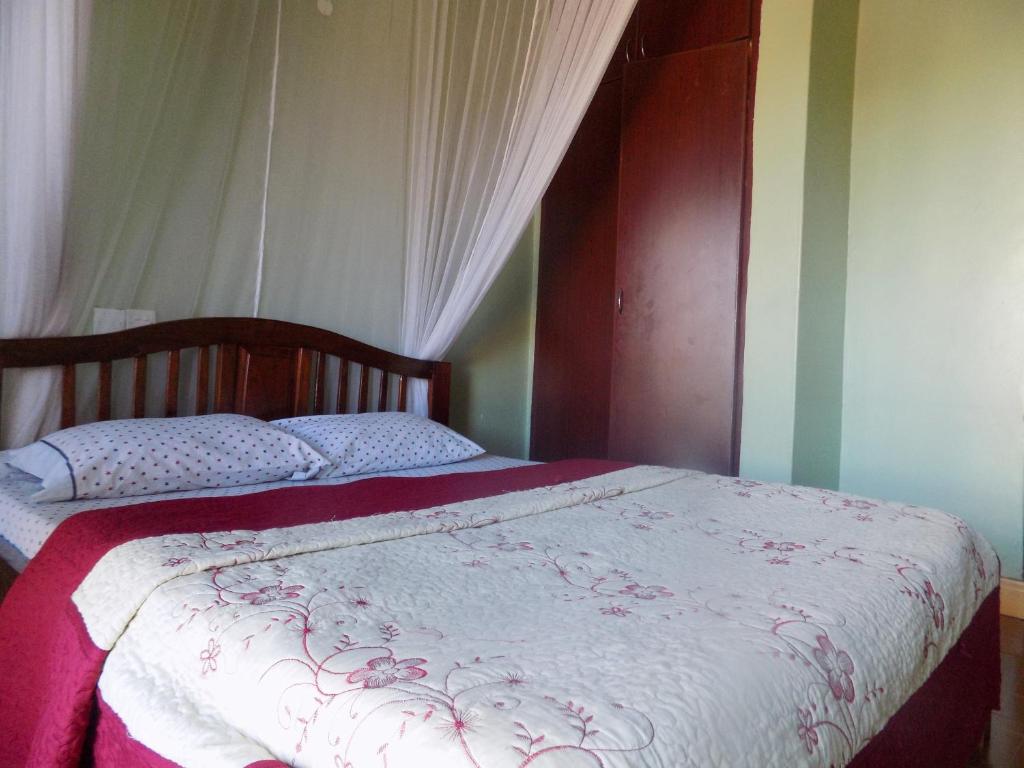 1 dormitorio con 1 cama con manta roja y blanca en Hotel Shine Sunet en Mbarara