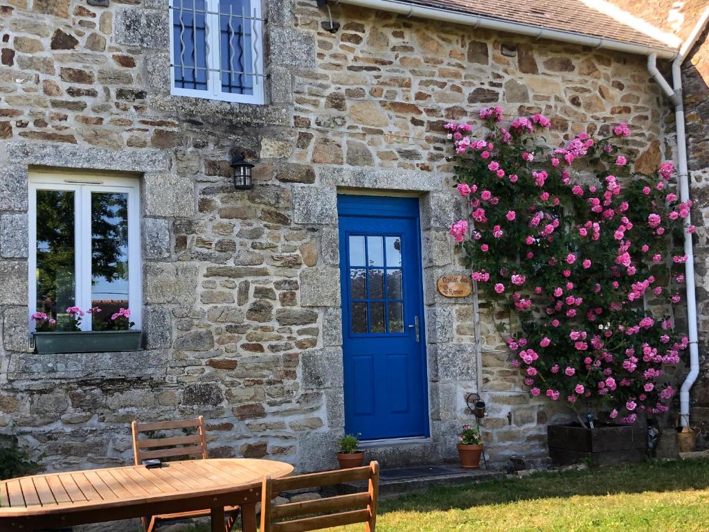 a stone house with a blue door and pink flowers at Pinabre Rose Cottage in Plouguenast Langast