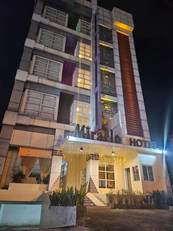 a hotel building at night with a sign on it at Miracle Hotel Manado in Manado