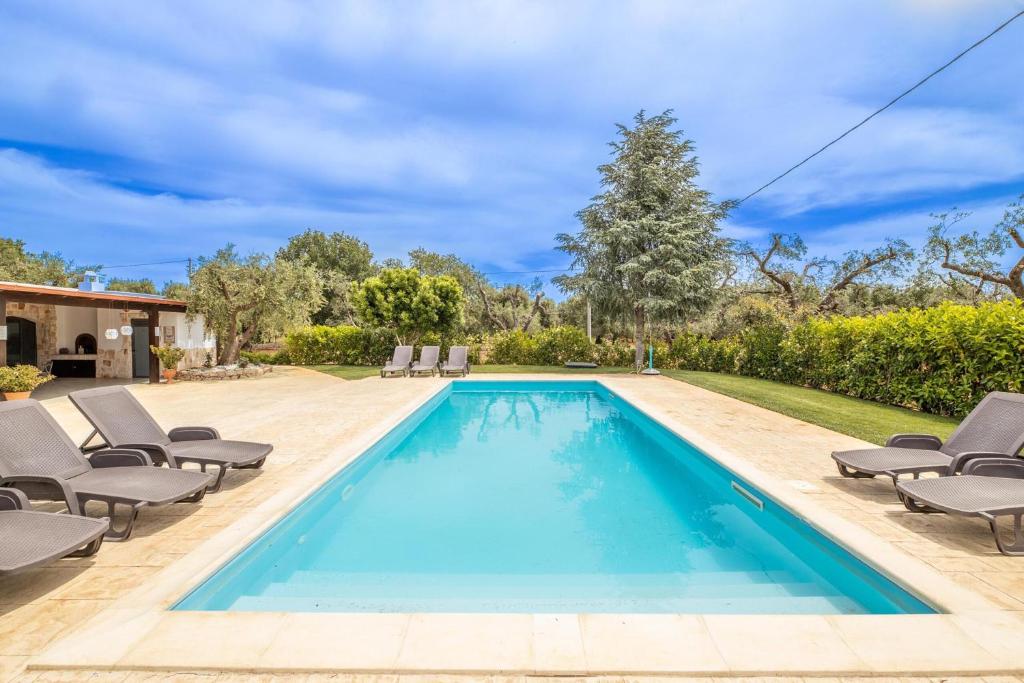 a swimming pool with lounge chairs next to a house at Trulli degli Augelli by BarbarHouse in San Michele Salentino