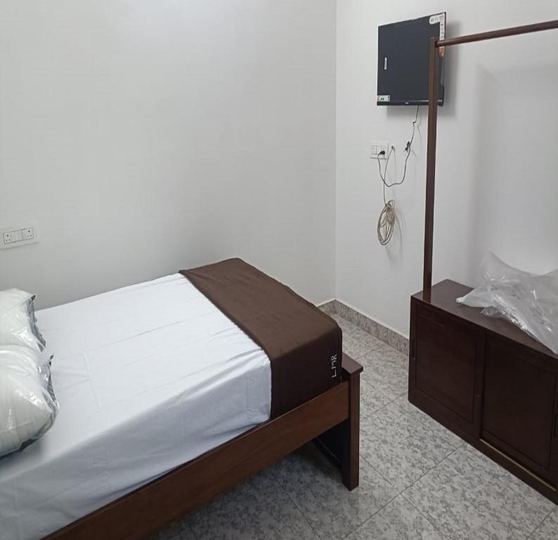 a bedroom with a bed and a dresser in it at Landmark Residency in Atirāmpattinam