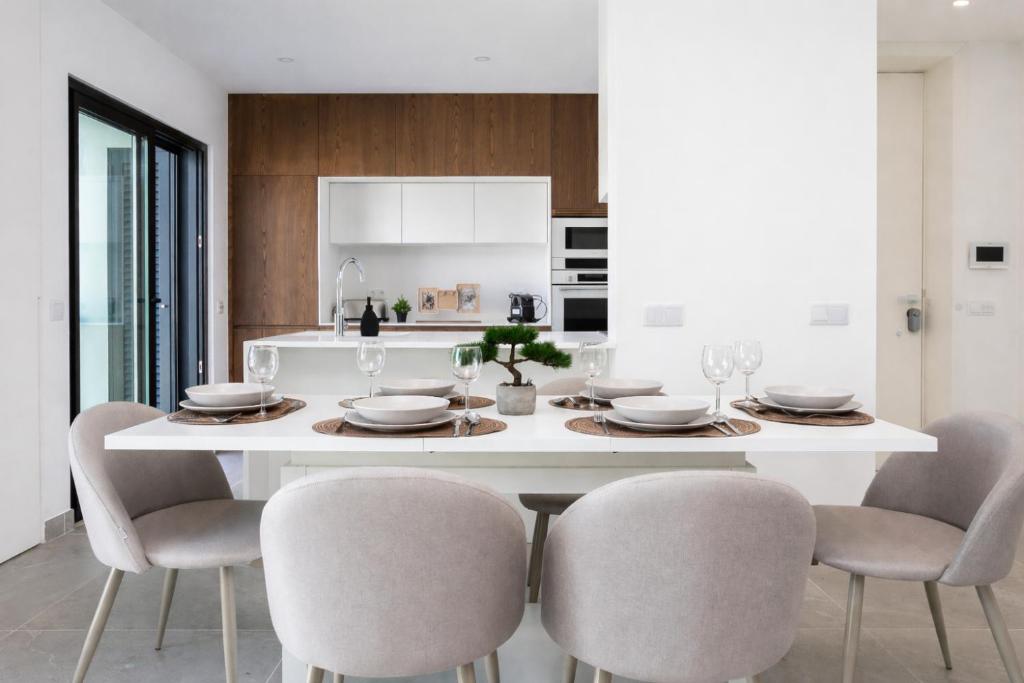a white dining room with a white table and chairs at Serena By Marenssa in Moncarapacho