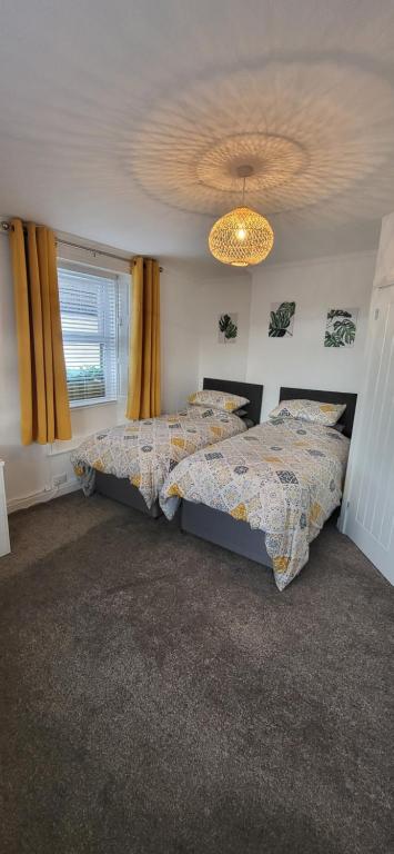 a bedroom with two beds and a chandelier at Miners Arms in Workington