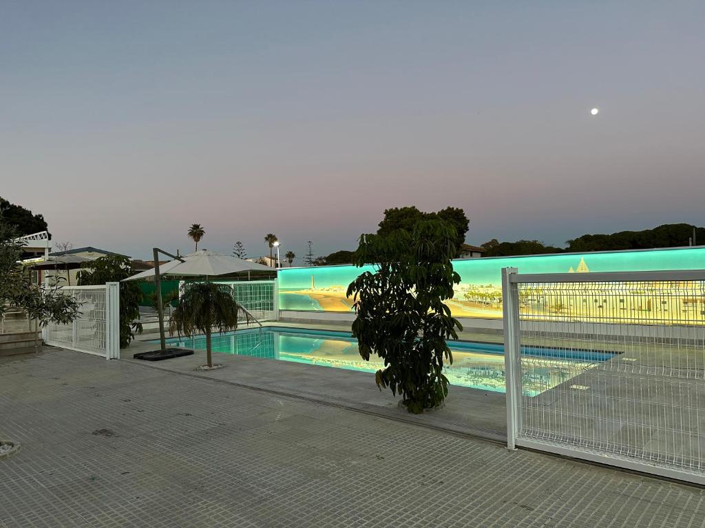 a swimming pool with a fence next to a building at Serenity Beach Pinar in Chipiona