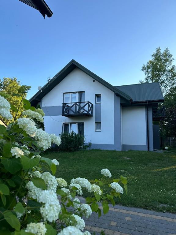 a white house with a balcony and flowers at Agroturystyka Pod Lasem na Roztoczu in Sochy