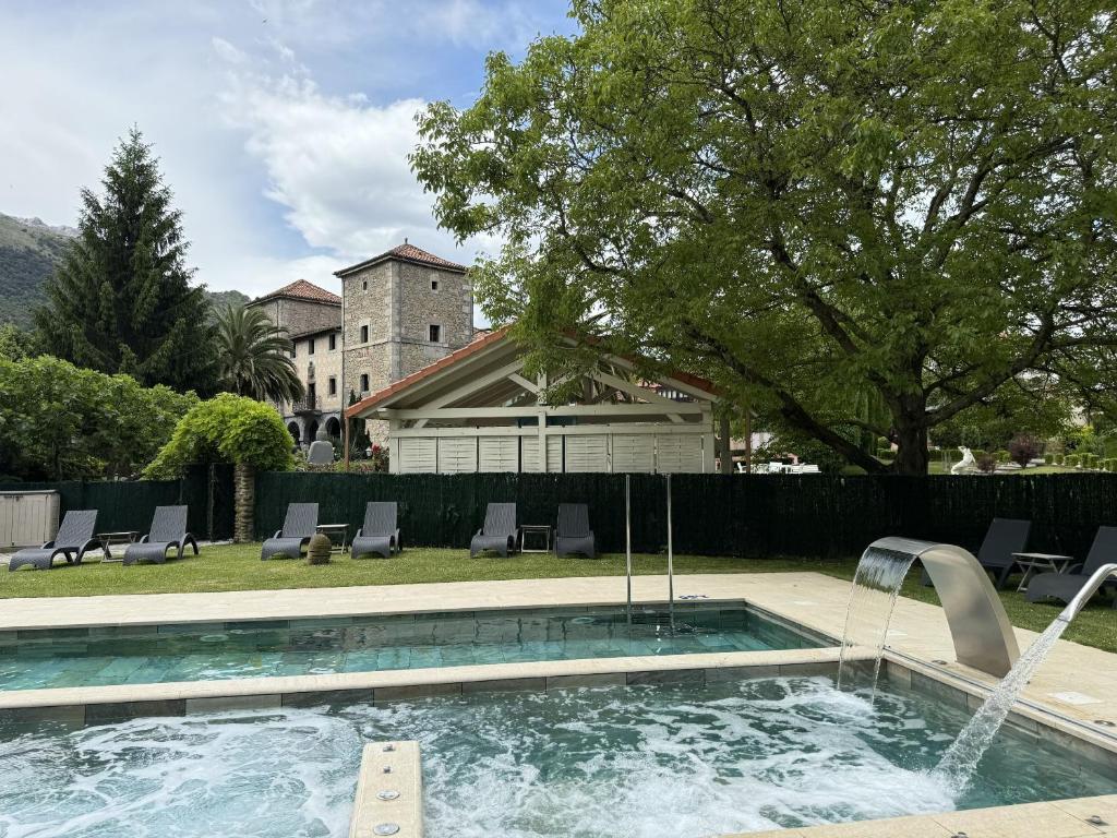 a swimming pool with a fountain in a yard at Akla Hotel Palacio Torre de Ruesga in Gibaja