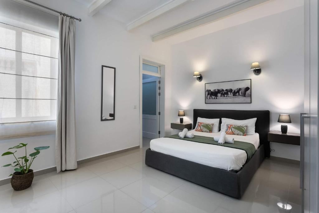 a bedroom with a large bed and a window at Four Bedroom Typical Maltese Townhouse - One Minute Away From The Seafront in Sliema