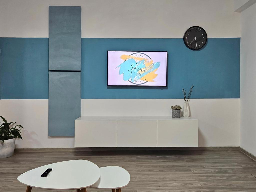 a living room with a white table and a clock at Hey! Central Apartment in Gheorgheni