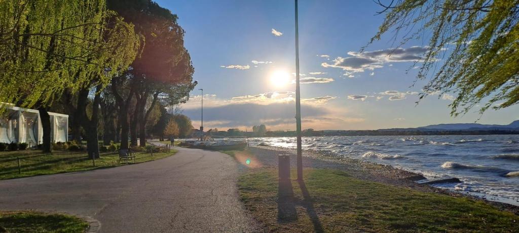 a street next to a body of water with the sun at Gg Home in Sirmione