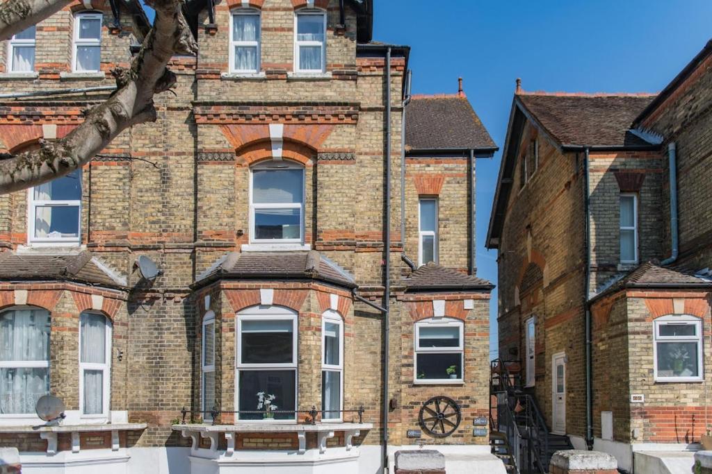 a large brick building with windows on a street at Folkestone Apartments in Folkestone