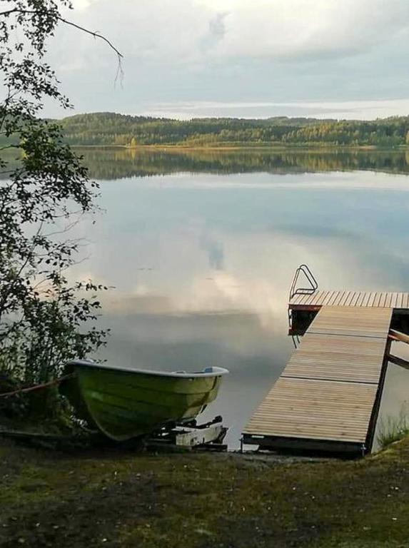 a boat sitting next to a dock on a lake at Itärajan Helmi in Tohmajärvi