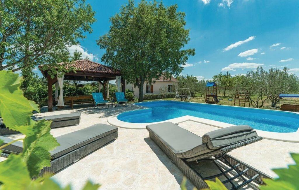 a swimming pool with chairs and a gazebo at House Back to nature in Drniš