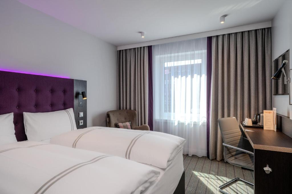 a hotel room with two beds and a desk at Premier Inn Hannover City Centre in Hannover