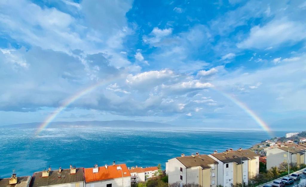 a rainbow in the sky over a city and the ocean at Apartman ELENA in Senj