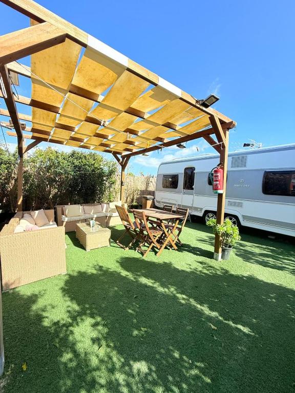 a picnic table and chairs under a wooden pergola at Caravana Con encanto 5 in El Palmar