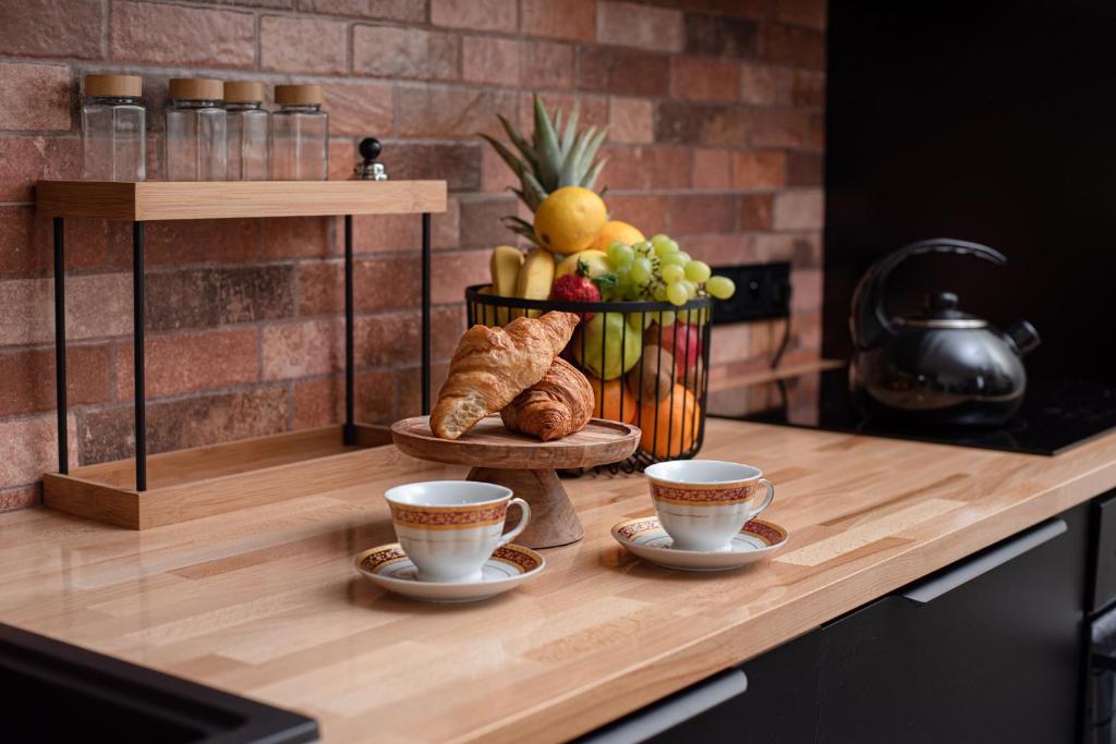 a counter with two cups of coffee and a basket of fruit at Apartament Podchorążych Dęblin in Dęblin